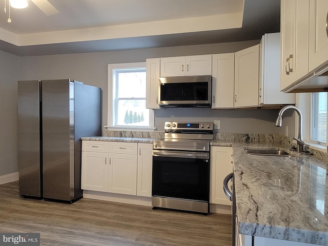 kitchen featuring appliances with stainless steel finishes, light wood-type flooring, white cabinets, and a sink