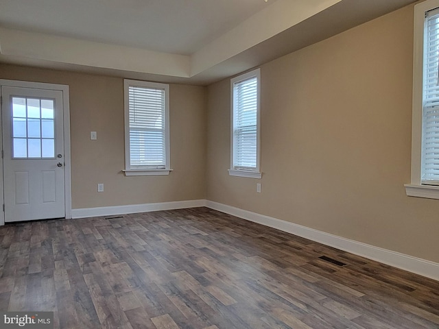 foyer entrance featuring visible vents, baseboards, and dark wood-style flooring