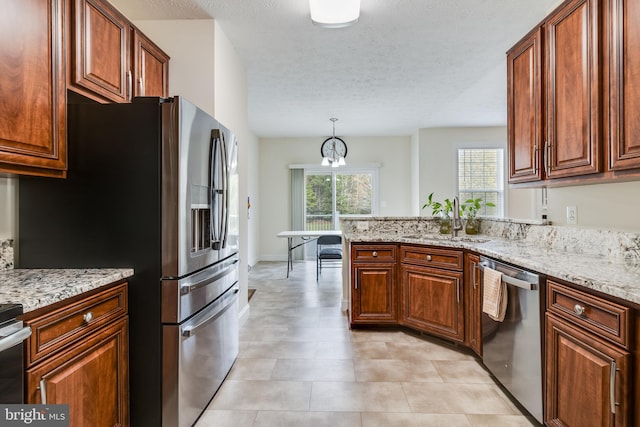 kitchen with stainless steel appliances, a healthy amount of sunlight, a sink, and light stone countertops