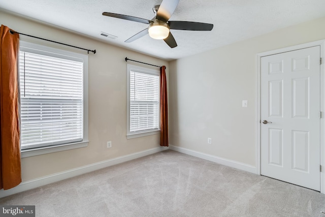 unfurnished room featuring baseboards, visible vents, a ceiling fan, a textured ceiling, and carpet flooring