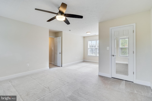 spare room with light carpet, baseboards, and a textured ceiling