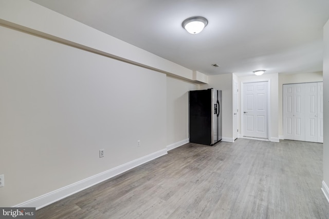 basement featuring fridge with ice dispenser, wood finished floors, visible vents, and baseboards