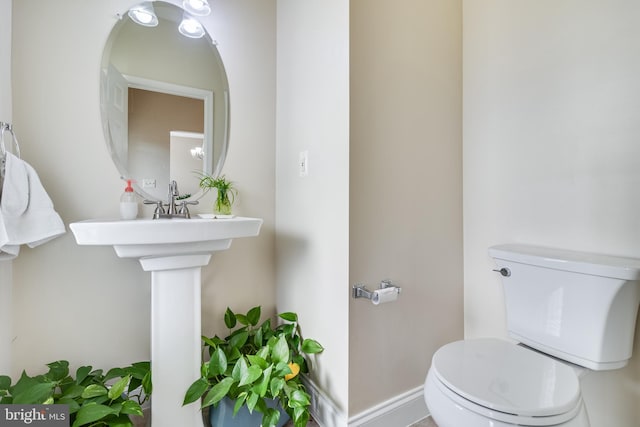 half bathroom featuring baseboards and toilet