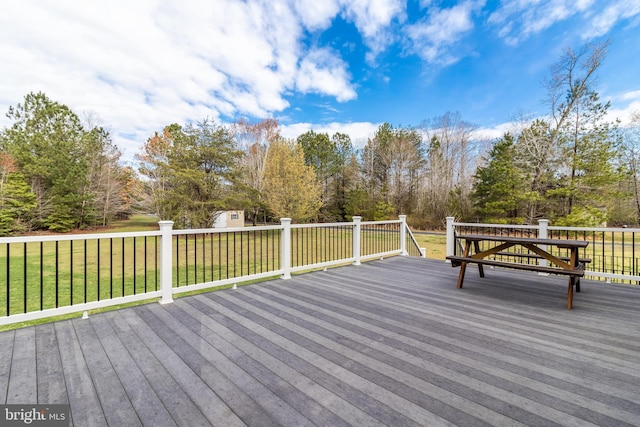 wooden deck with a storage shed, a lawn, and an outbuilding