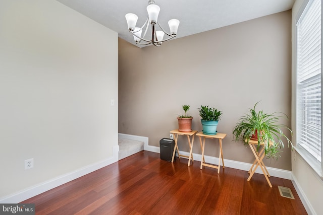 interior space with visible vents, a notable chandelier, baseboards, and wood finished floors