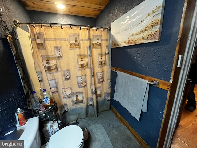 full bathroom featuring a textured wall, wooden ceiling, toilet, and a shower with curtain