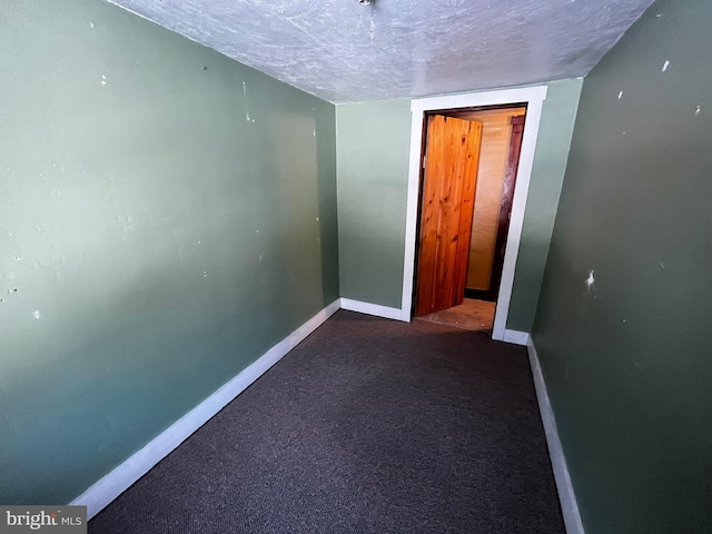 empty room with carpet, a textured ceiling, and baseboards