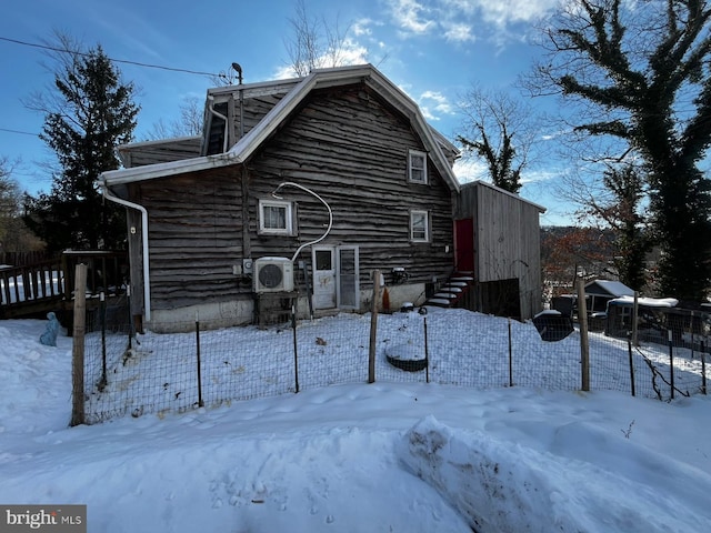 snow covered property with ac unit, fence, a gambrel roof, and entry steps