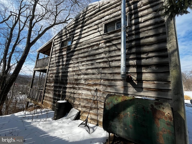 view of snow covered exterior featuring a balcony and heating fuel