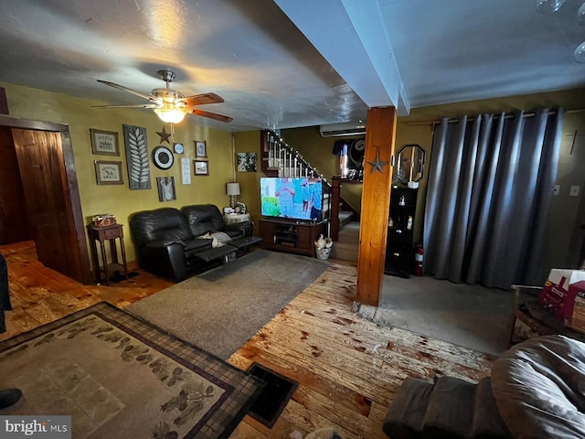 living area with ceiling fan and stairway