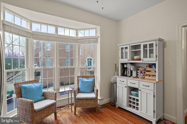 living area with light wood-type flooring, visible vents, and baseboards