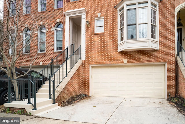 view of property with concrete driveway, brick siding, and an attached garage