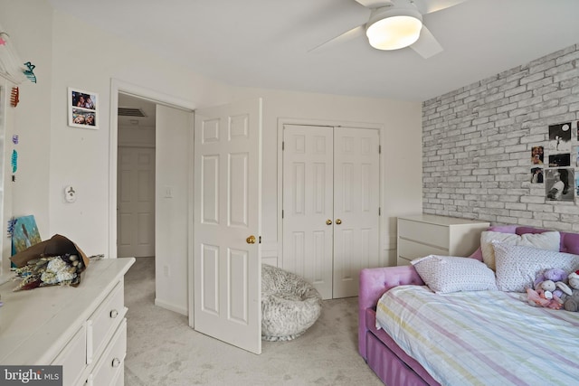 bedroom with visible vents, a ceiling fan, light colored carpet, brick wall, and a closet