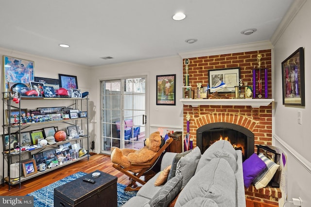 living area featuring wainscoting, a fireplace, crown molding, and wood finished floors