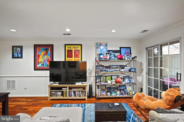 living area with wood finished floors, visible vents, and crown molding