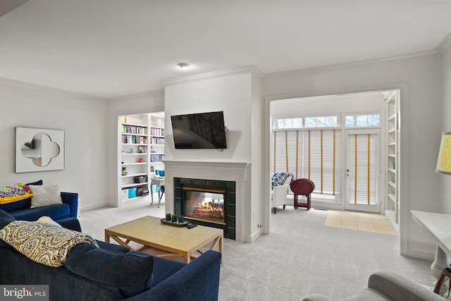 living area featuring carpet floors, baseboards, ornamental molding, and a tiled fireplace