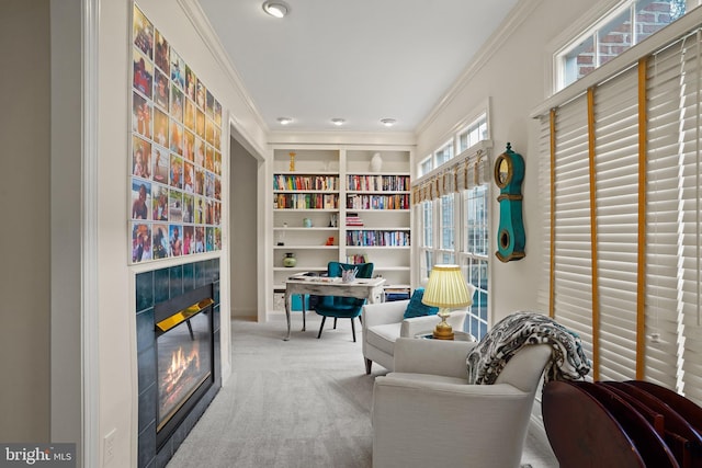 sitting room with built in shelves, a glass covered fireplace, carpet flooring, and crown molding