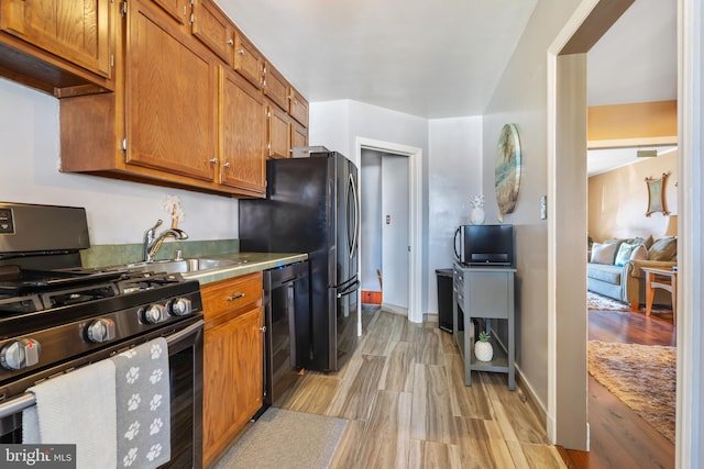 kitchen featuring stainless steel gas range oven, wine cooler, brown cabinets, and freestanding refrigerator