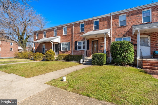 townhome / multi-family property featuring a front yard and brick siding