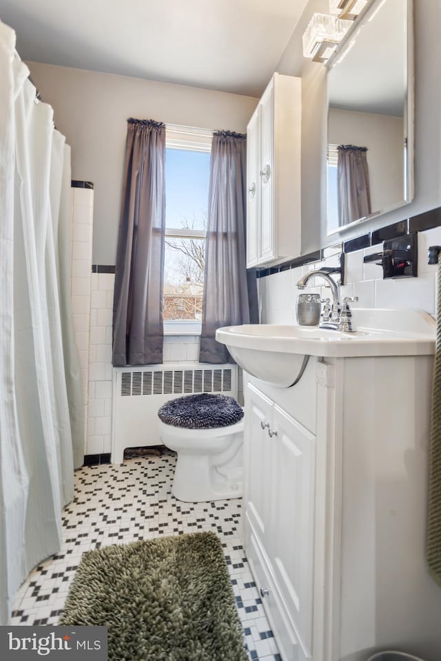 bathroom featuring radiator, a shower with curtain, toilet, vanity, and tile walls