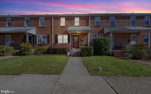 townhome / multi-family property with brick siding and a front lawn