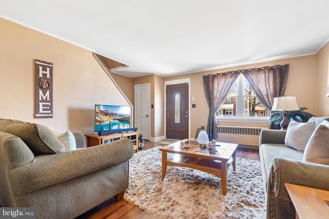 living room with radiator, baseboards, ornamental molding, and wood finished floors