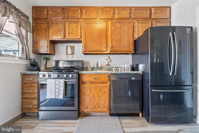 kitchen featuring gas stove, freestanding refrigerator, brown cabinets, and dishwashing machine