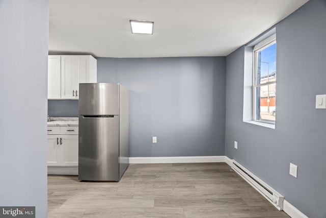 kitchen featuring freestanding refrigerator, baseboards, white cabinetry, and baseboard heating