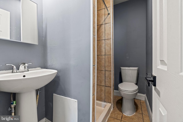 bathroom featuring tile patterned flooring, a shower stall, toilet, and baseboards