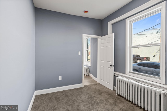 bedroom featuring dark colored carpet, radiator, and baseboards