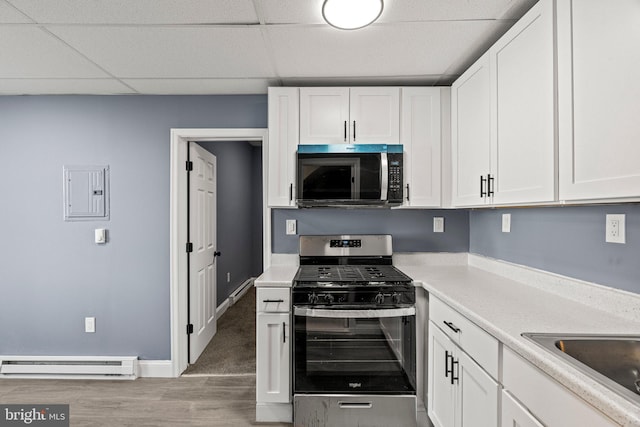 kitchen with electric panel, white cabinets, baseboard heating, stainless steel appliances, and light countertops