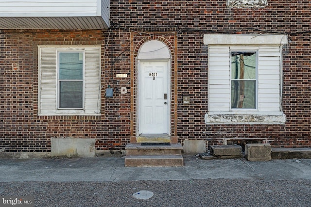 entrance to property featuring brick siding