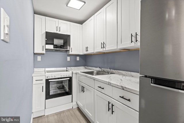 kitchen with white cabinets, electric stove, freestanding refrigerator, black microwave, and a sink