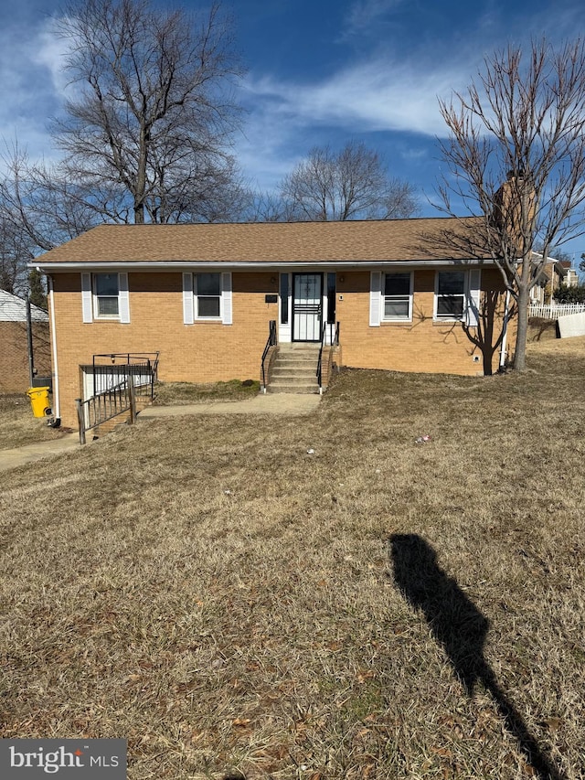 view of front of property featuring brick siding, a front yard, and a shingled roof