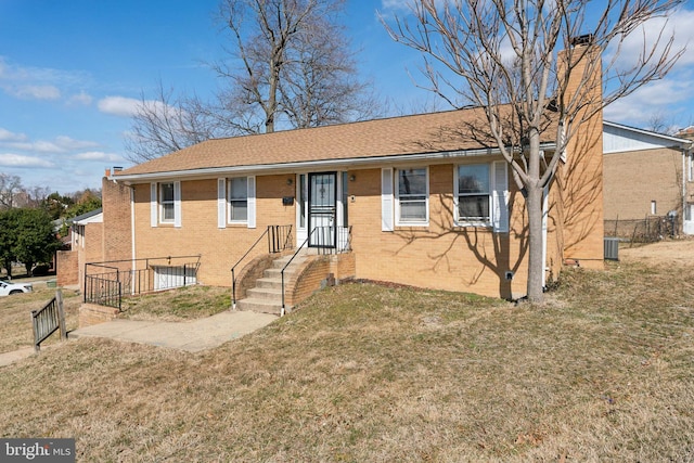 view of front of home with central air condition unit, fence, a front lawn, and brick siding