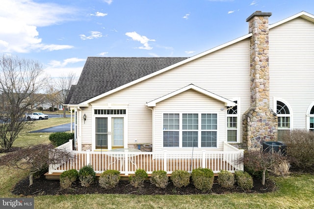 back of house featuring a deck, french doors, roof with shingles, and a chimney