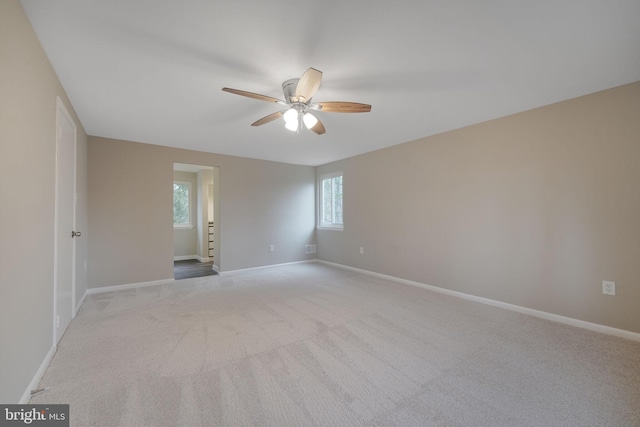 carpeted spare room featuring ceiling fan and baseboards