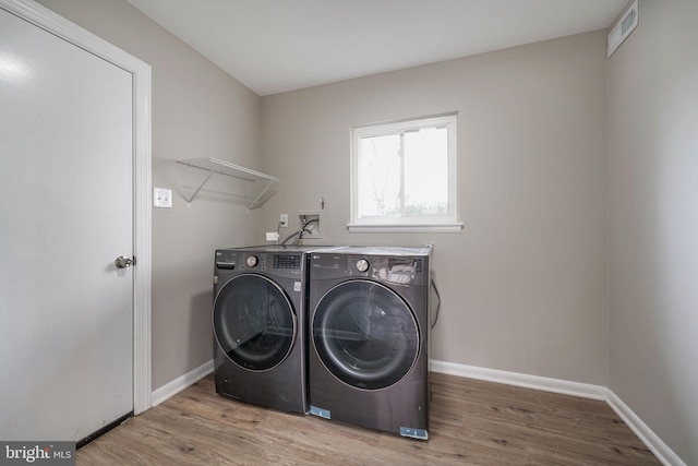 washroom with laundry area, separate washer and dryer, wood finished floors, visible vents, and baseboards