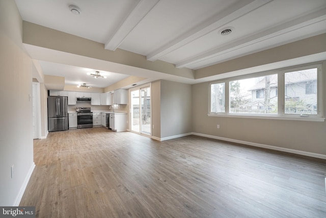 unfurnished living room with baseboards, visible vents, and a wealth of natural light