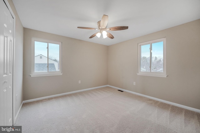 unfurnished bedroom with multiple windows, carpet, visible vents, and baseboards