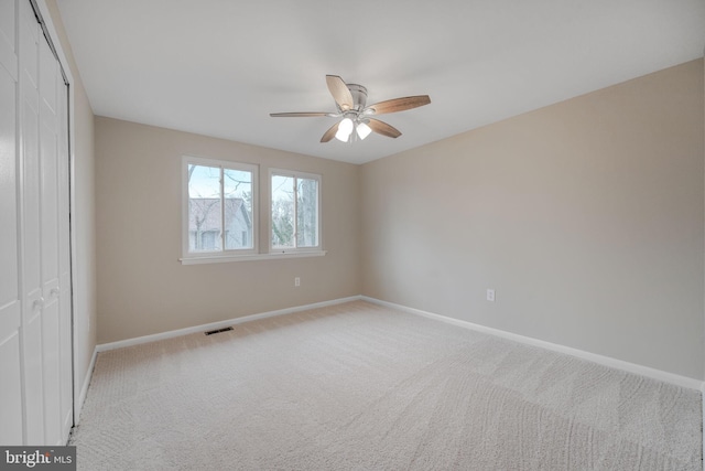 empty room with baseboards, visible vents, ceiling fan, and carpet flooring