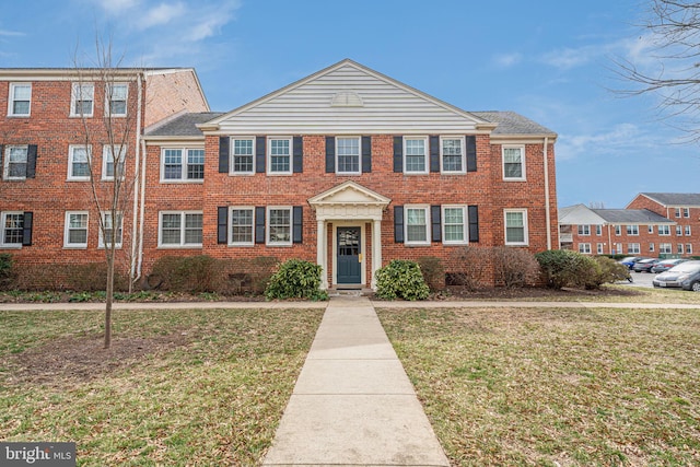 townhome / multi-family property featuring a front yard and brick siding