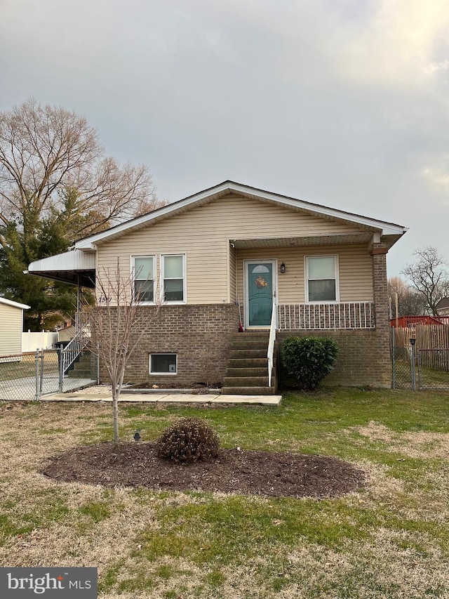 view of front of home with a front yard, a gate, brick siding, and fence