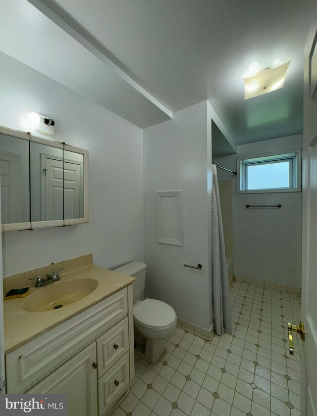 bathroom featuring toilet, vanity, and a shower with curtain