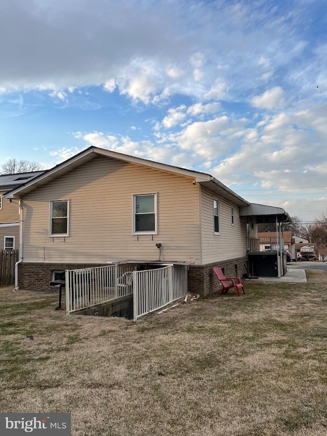 back of property featuring a lawn and brick siding