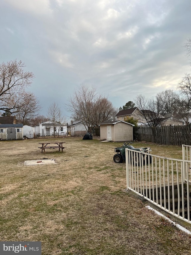 view of yard featuring an outbuilding, fence, and a storage shed