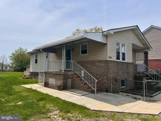 view of front of home with a front lawn, brick siding, fence, and stairs