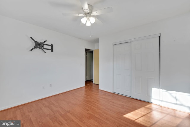 unfurnished bedroom featuring a ceiling fan, a closet, baseboards, and wood finished floors