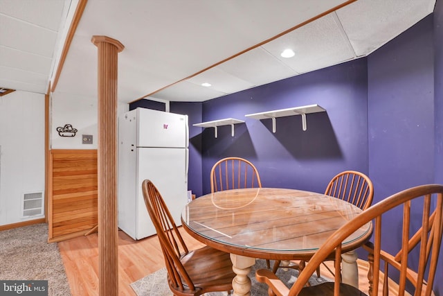 dining space featuring a wainscoted wall, decorative columns, visible vents, light wood-style flooring, and wooden walls