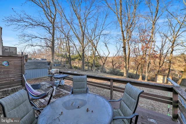 wooden deck featuring outdoor dining area, an outdoor structure, and a storage shed